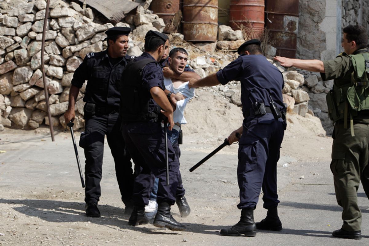 An Israeli soldier gestures as Palestinian policemen detain a youth during clashes in the West Bank city of Hebron September 21, 2011.        (Ammar Awad / Reuters)