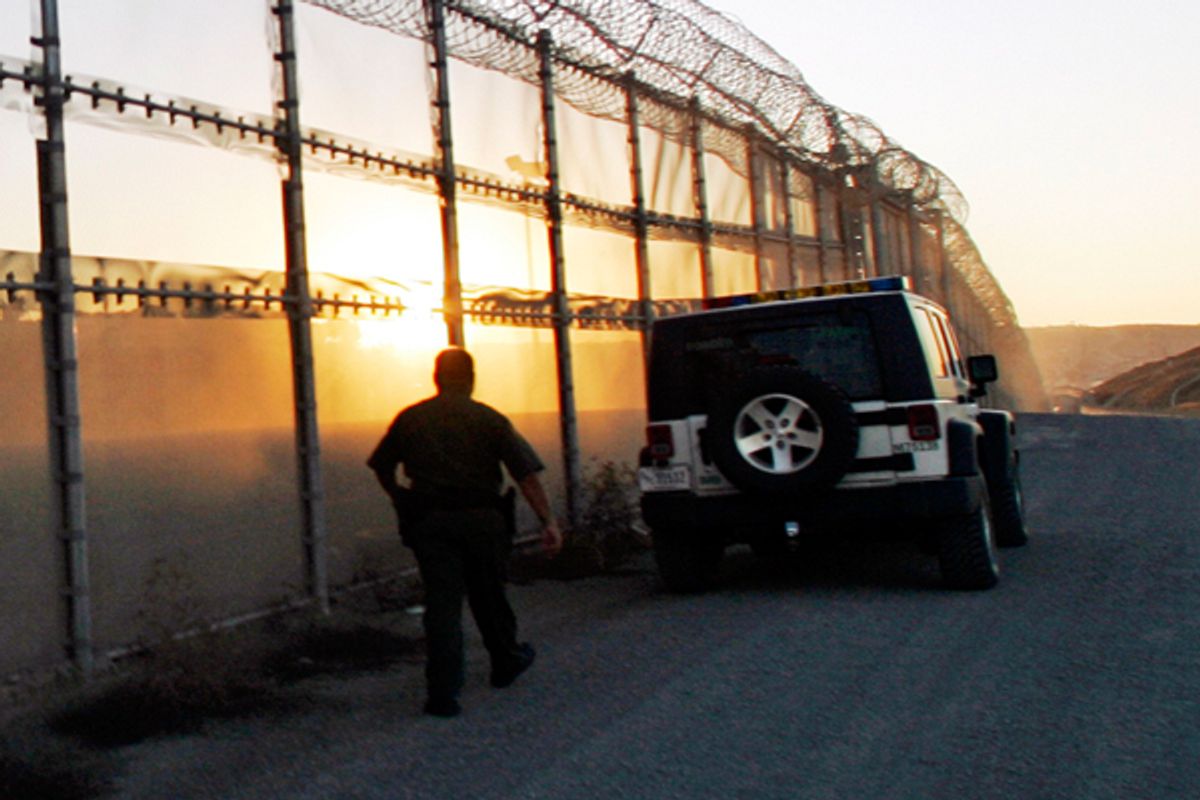 A U.S. Border Patrol agent walks along the U.S./Mexico border fence near San Diego. 
  (AP/Lenny Ignelzi)