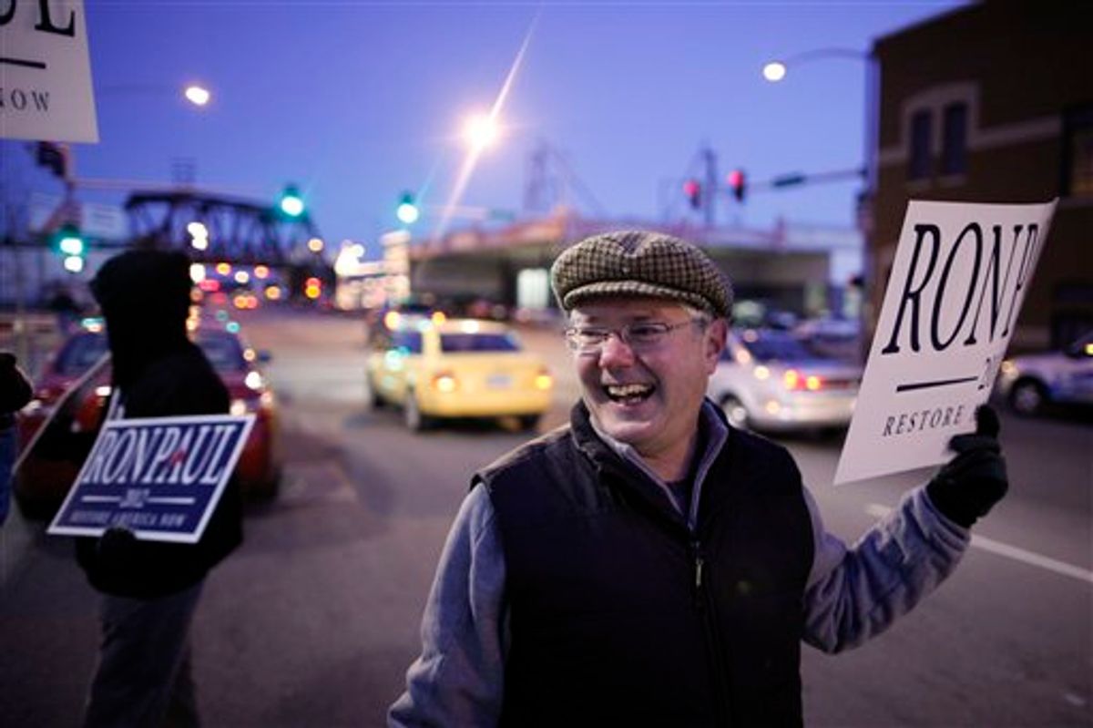 Chris Noth, a Ron Paul supporter, holds up a sign outside Mitt Romney's campaign stop in Davenport, Iowa, Dec. 27, 2011.         (AP Photo/Chris Carlson)