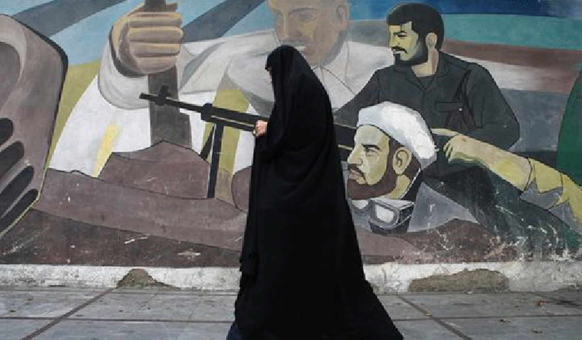  In this Tuesday, Oct. 18, 2011 photo, an Iranian woman walks past a mural depicting members of Basij paramilitary force, portraying Iranians' solidarity against their enemies, in Tehran, Iran.      (AP Photo/Vahid Salemi)