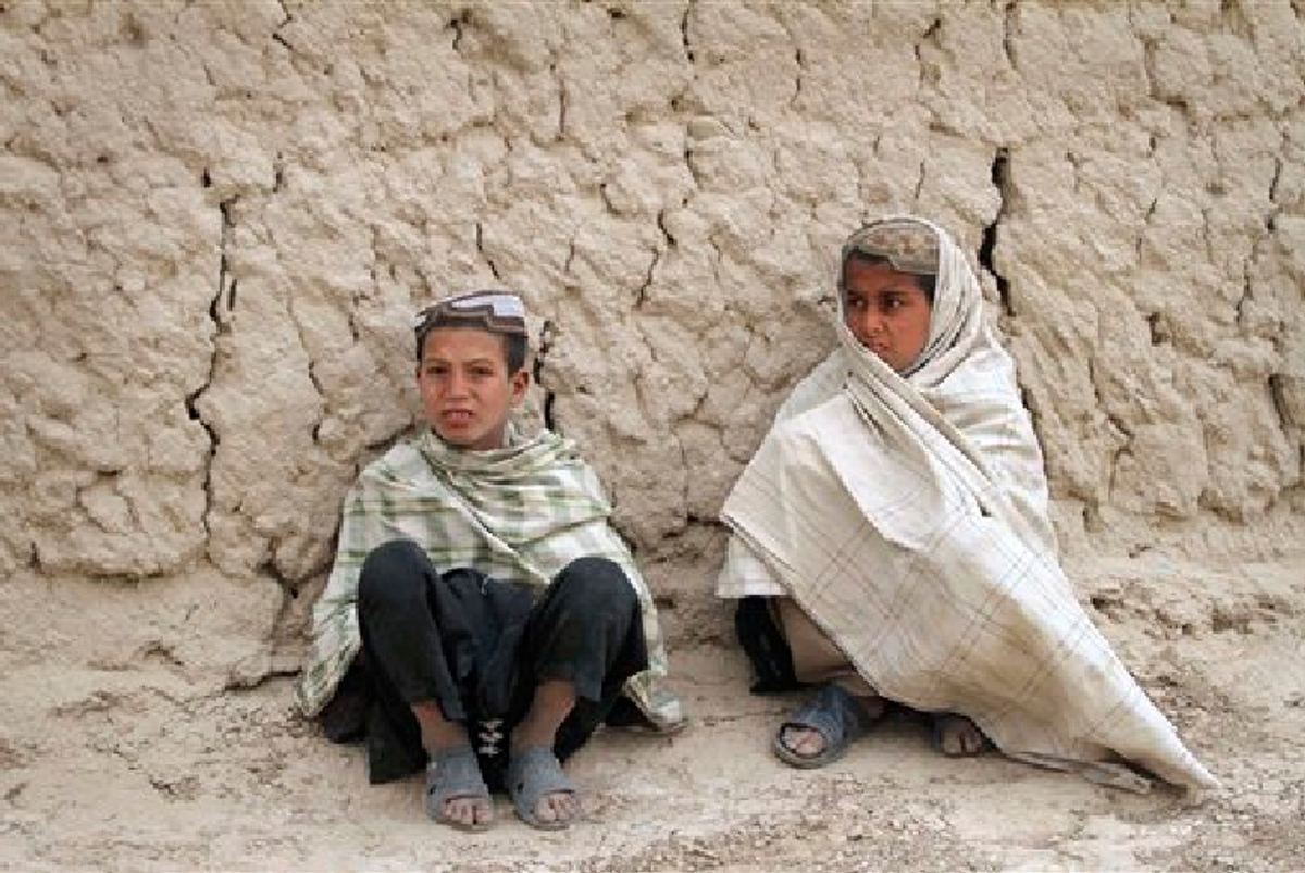 Afghan boys sit on the ground near the scene where Afghans were allegedly killed by a U.S. service member in Panjwai, Kandahar province south of Kabul, Afghanistan, Sunday, March. 11, 2012. (AP Photo/Allauddin Khan)