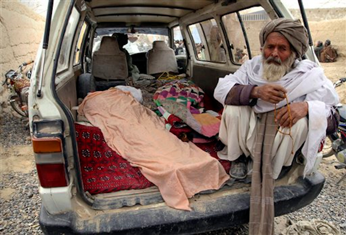 An elderly Afghan man sits next to the covered body of a person who was allegedly killed by a U.S. service member, in a minibus in Panjwai, Kandahar province south of Kabul, Afghanistan, Sunday, March 11, 2012     (AP Photo/Allauddin Khan)