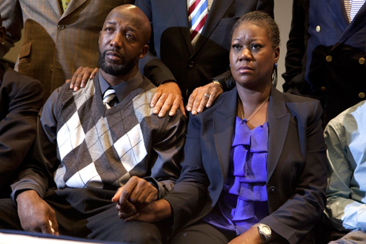 The parents of Trayvon Martin, Sybrina Fulton, right, and Tracy Martin hold hands as they watch a news conference announcing charges against George Zimmerman.    (AP/Evan Vucci)
