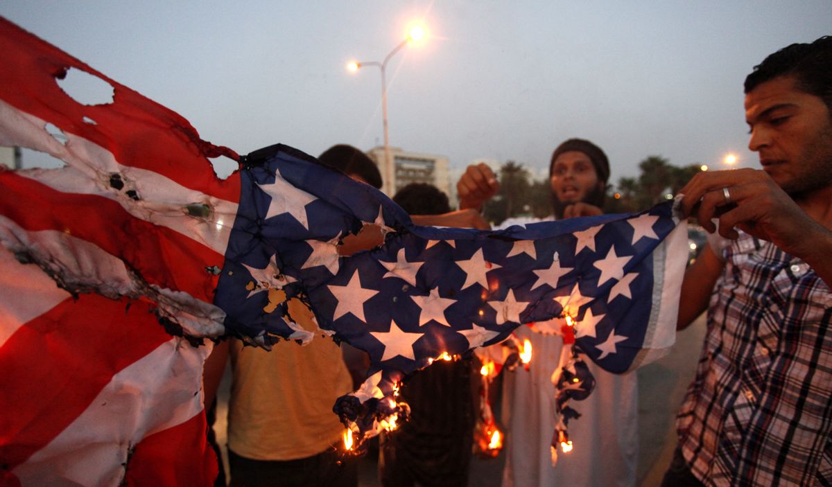 Libyan followers of Ansar al-Shariah Brigades burn the U.S. flag during a protest in front of the Tibesti Hotel, in Benghazi, Libya      (AP/ Mohammad Hannon)