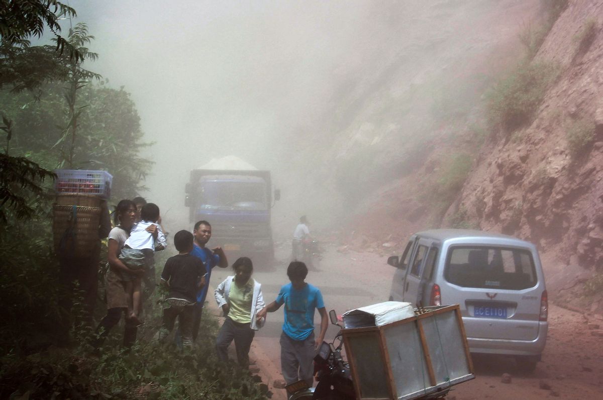 People run as rocks fall near their vehicles after the area was hit by an earthquake in Zhaotong town, Yiliang County, southwest China's Yunnan Province, Friday, Sept. 7, 2012. (AP Photo) CHINA OUT  