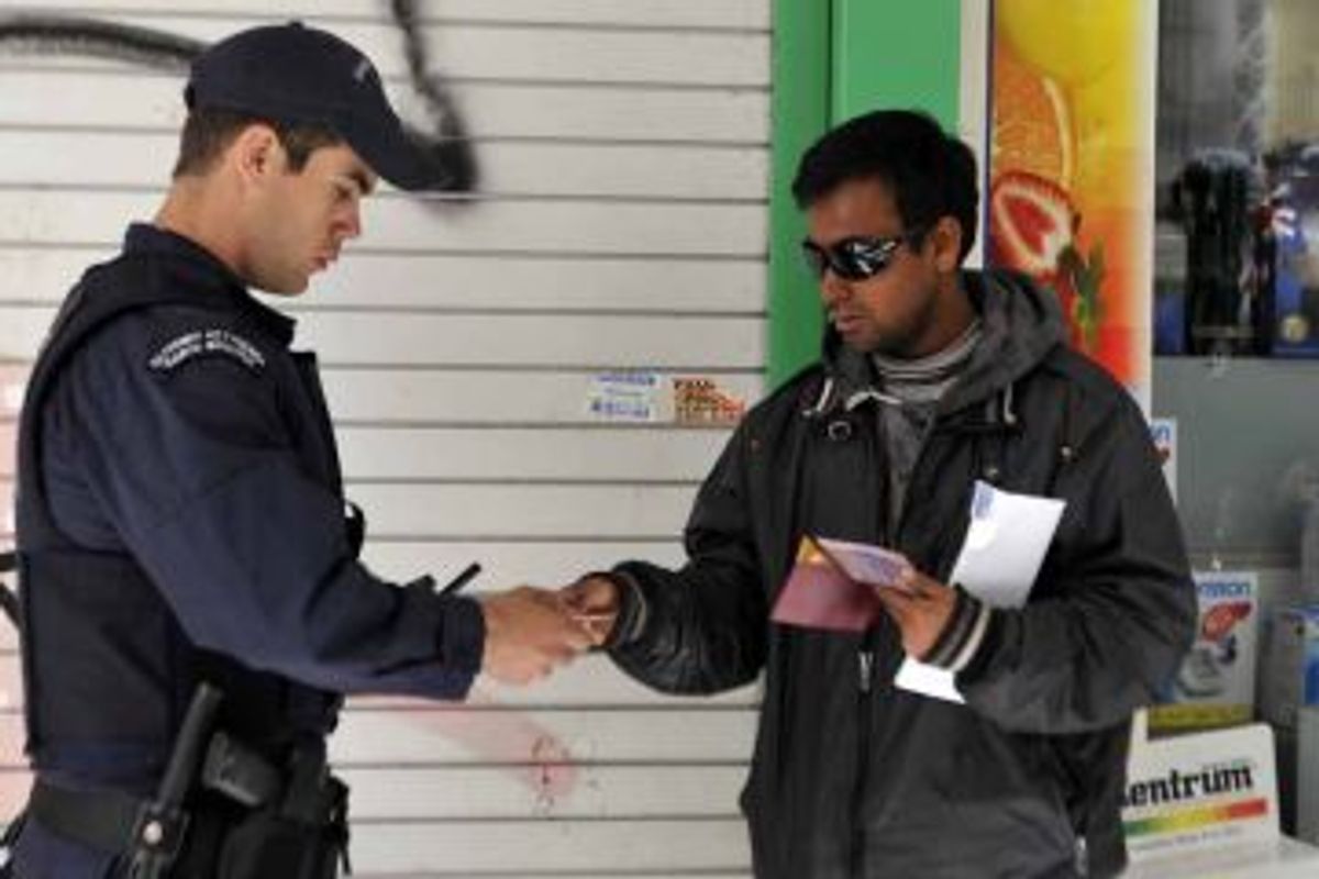Police check an immigrant's papers in central Athens' Omonia square area.        (Louisa Gouliamaki//Getty Images)
