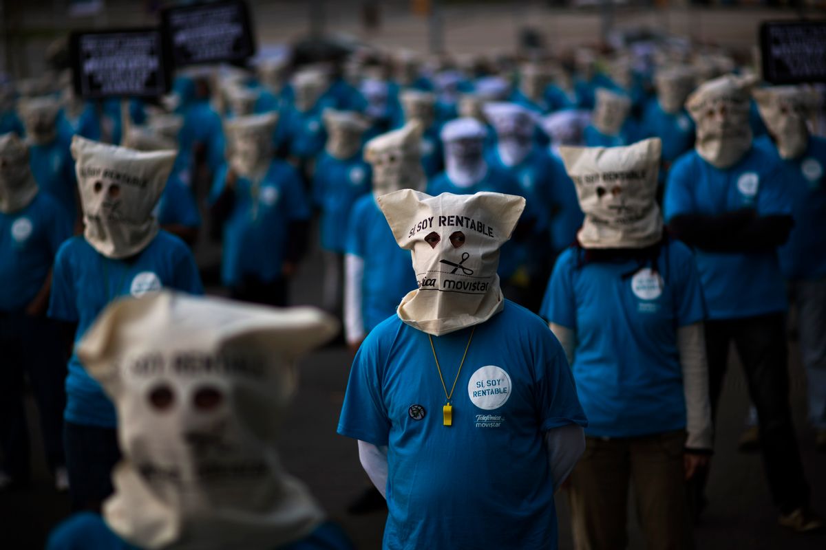 Masked demonstrators, employees from the Telefonica phone company, protest on a street near a building where executives from the same company are participating in a business meeting in Barcelona, Spain     (AP/Emilio Morenatti)