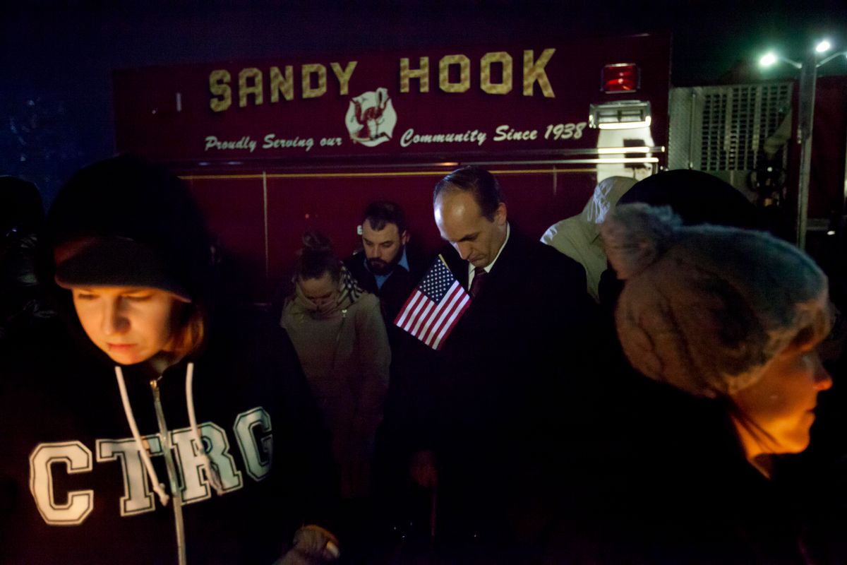Mourners listen to a memorial service over a loudspeaker outside Newtown High School for the victims of the Sandy Hook Elementary School shooting.       (AP/David Goldman)