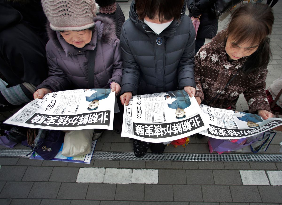 Passers-by read a delivered extra edition of a Japanese newspaper reporting North Korea's nuclear test, in Tokyo Tuesday, Feb. 12, 2013.              (AP/Itsuo Inouye)