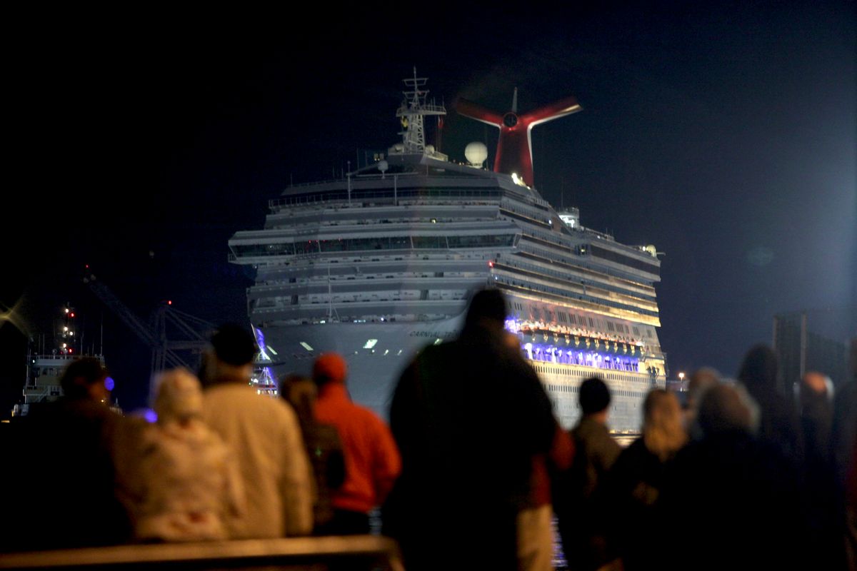 The Carnival Triumph cruise ship is towed toward the dock as spectators watch at the port of Mobile, Ala.   (Reuters)
