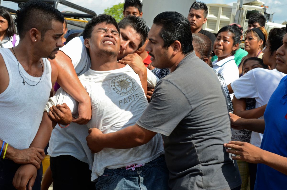 A distraught relative is held back after three men on a public bus were killed by unknown gunmen in the Pacific resort city of Acapulco, Mexico, Monday March 1, 2013.       (AP/Bernandino Hernandez)