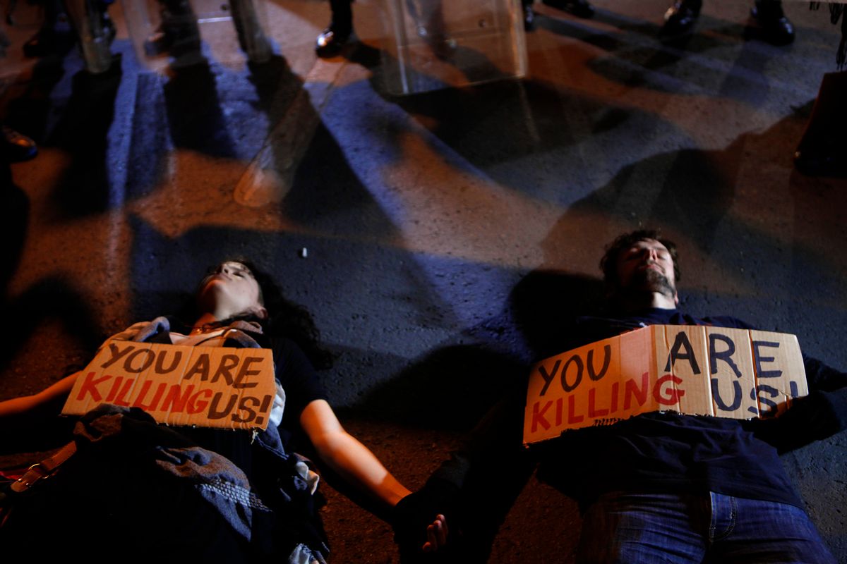 Protesters line on the ground in front of riot police in Nicosia, Cyprus.     (AP/Petros Karadjias)