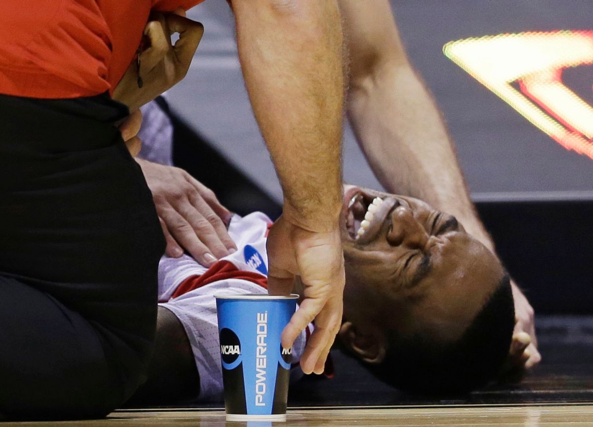  

Louisville guard KevinWare grimaces as trainers look at his injury during the first half of the Midwest Regional final against Duke in the NCAA college basketball tournament on Sunday.    
