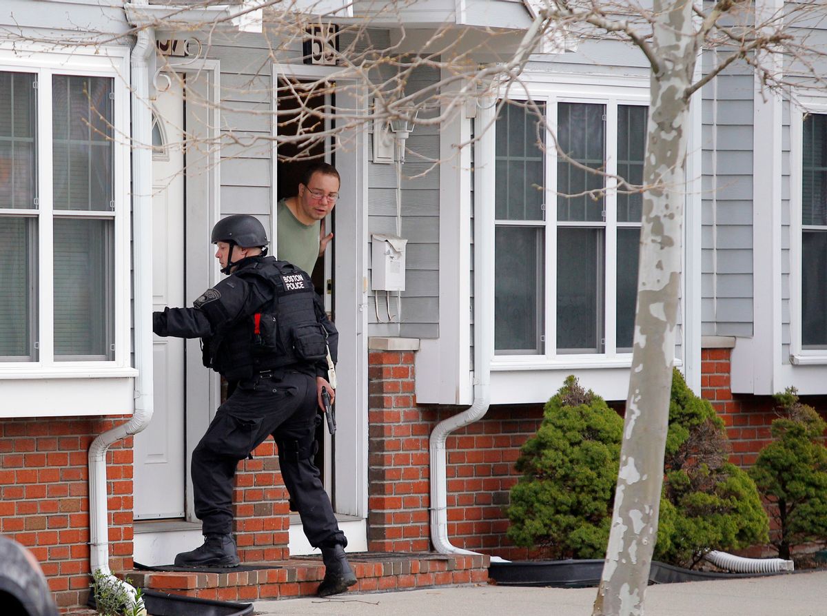 A man looks out his door as a SWAT team member knocks on his neighbor's door as they search for the remaining suspect in the Boston Marathon bombings in Watertown, Mass., April 19, 2013.                         (Reuters)
