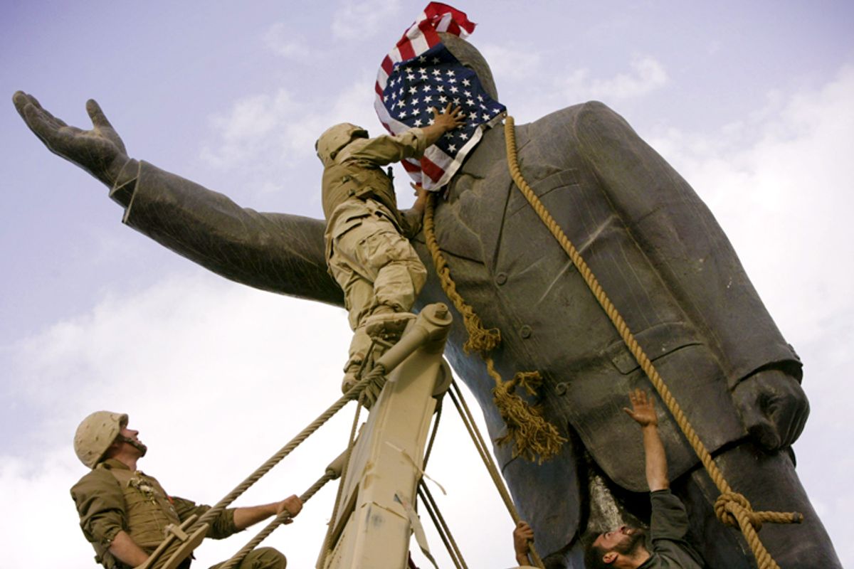 Cpl. Edward Chin, of the 3rd Battalion, 4th Marines Regiment, covers the face of a statue of Saddam Hussein with an American flag before toppling the statue in downtown in Bagdhad Wednesday, April 9, 2003. Moments later the American flag was removed.    (AP/Jerome Delay)