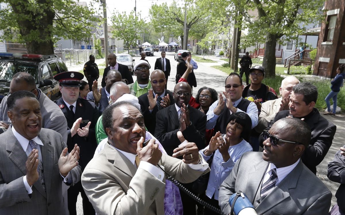 Pastor Larry Harris, center, leads a prayer vigil near the home where three women held captive for a decade, in Cleveland, Ohio, Wednesday, May 8, 2013.     (AP/David Duprey)