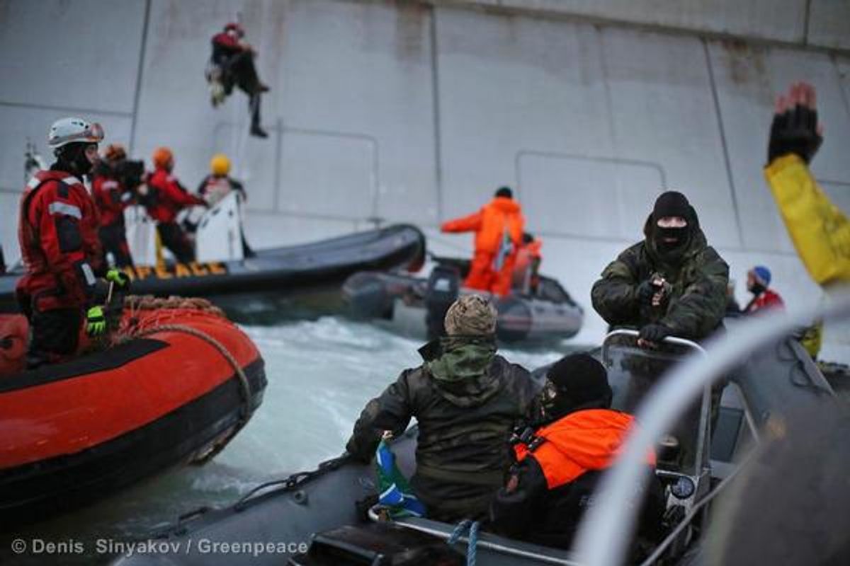 A Russian Coast guard officer is seen pointing a gun at a Greenpeace International activist as five activists attempt to climb the 'Prirazlomnaya,' an oil platform operated by Russian state-owned energy giant Gazprom platform in Russias Pechora Sea.  (Denis  Sinyakov/Greenpeace)