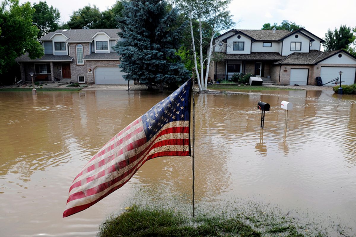 A muddy U.S. flag stands in front of flooded homes in Longmont, Colo., on Sept. 14, 2013.       (AP/Chris Schneider)
