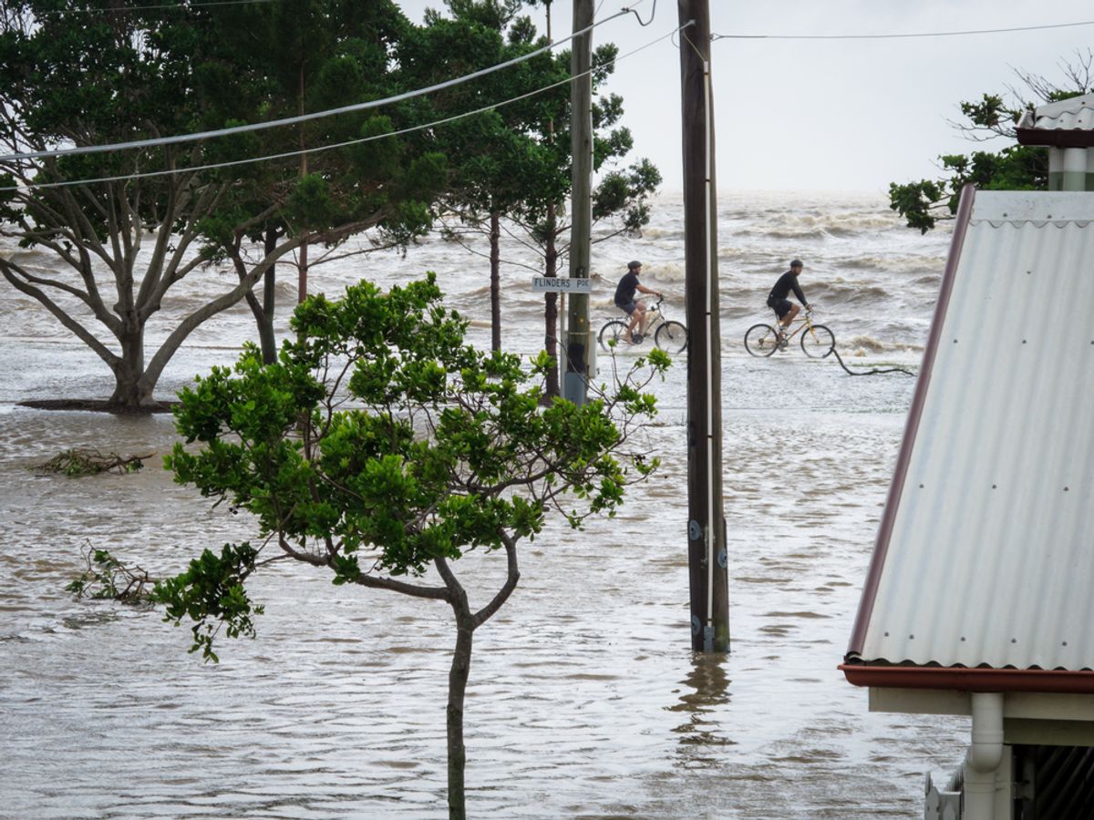 A pair of cyclists ride along the sea wall during the storm surge floods in Brisbane, Australia on January 27, 2013.    (Silken Photography/Shutterstock)