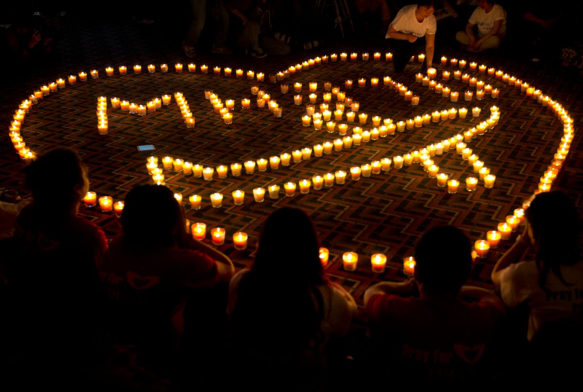 A woman arranges a candle as relatives of Chinese passengers onboard Malaysia Airlines Flight 370 offer prayer during a candlelight vigil for their loved ones at a hotel in Beijing, China, late Tuesday, April 8, 2014. An Australian ship is reported to have detected two distinct, long-lasting sounds underwater that are consistent with the 'pings' signal from aircraft black boxes, and is being seen as a possible advance in the month long hunt for the missing Malaysia Airlines jet, but the 'pings' still have to be verified.  (AP Photo/Andy Wong)     (AP)