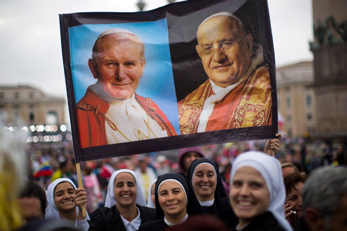 Nuns hold up a poster with portraits of  Pope John Paul II, left, and John XXIII, in St. Peter's Square at the Vatican, April 27, 2014.         (AP/Emilio Morenatti)