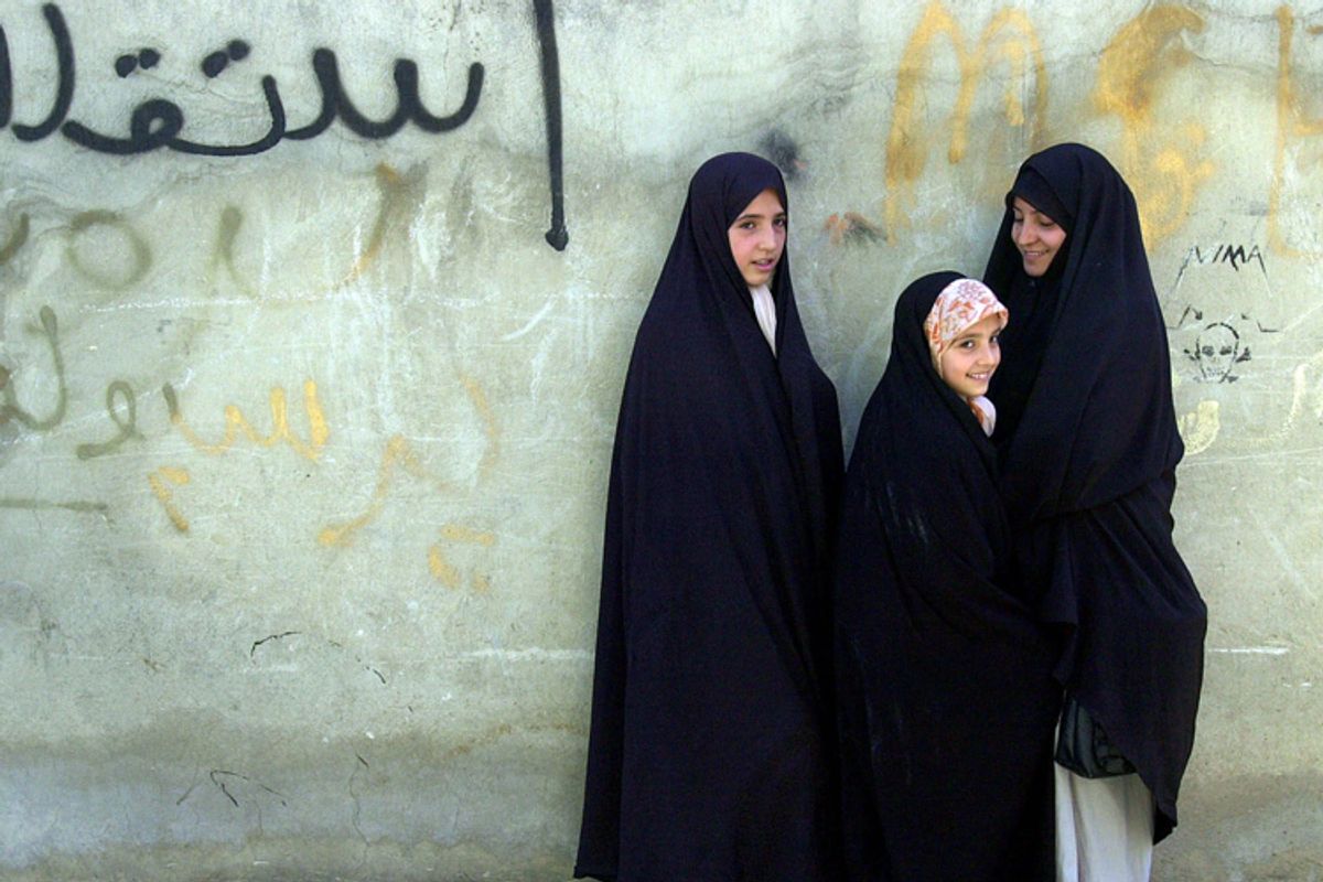 Three Iranian girls wearing traditional chadors at a mosque in northern Teh...