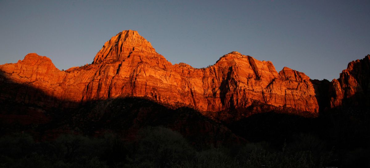 FILE - This Jan. 20, 2011 file photo shows shadows creeping up on sandstone cliffs glowing red as the sun sets on Zion National Park near Springdale, Utah. The National Park Service is taking steps to ban drones from 84 million acres of public lands and waterways, saying the unmanned aircraft annoy visitors, harass wildlife and threaten safety. Jonathan Jarvis, the park services director, told The Associated Press he was signing a policy memorandum on Friday directing superintendents of the services 401 parks to write rules prohibiting the launching, landing or operation of unmanned aircraft in their parks.  (AP Photo/Julie Jacobson, file) (AP Photo/Julie Jacobson, file)