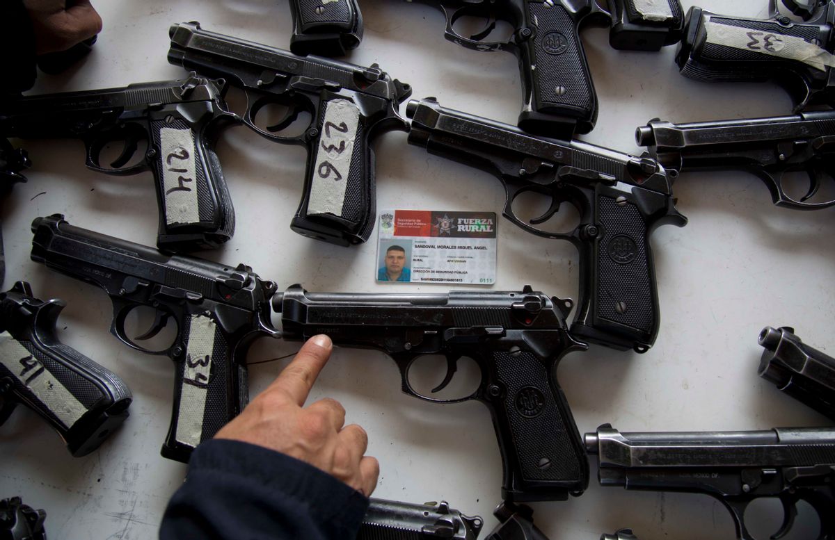 A federal police looks for the assigned weapon that corresponds to the rural police's identification card before the start of a ceremony in Tepalcatepec, Mexico, Saturday, May 10, 2014.     (Associated Press)