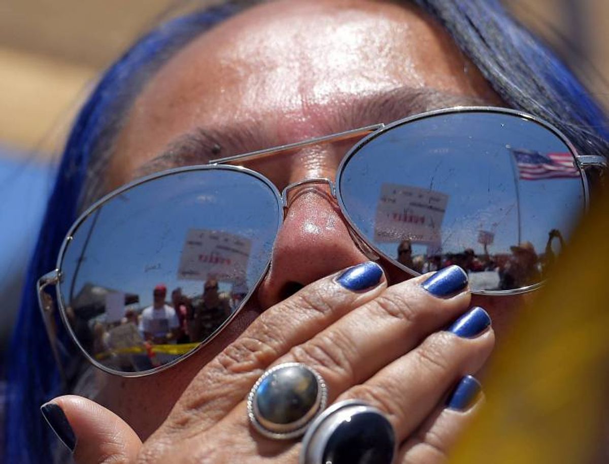 A pro-immigration demonstrator looks across a police line at the opposing side, Friday, July 4, 2014, outside a U.S. Border Patrol station in Murrieta, Calif.      (Associated Press)