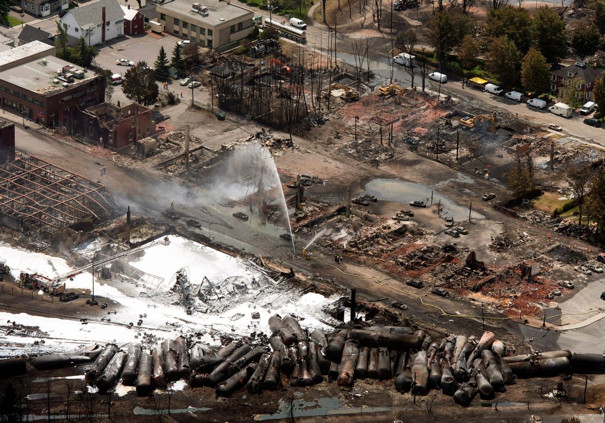 In this Sunday, July 7, 2013 photo, the downtown core is in ruins as firefighters water smoldering rubble in Lac-Megantic, Quebec, after a train derailed, igniting tanker cars carrying crude oil. Lac-Megantic still struggles to recover as it marks the disaster's one-year anniversary. (AP Photo/The Canadian Press, Ryan Remiorz)  (AP)