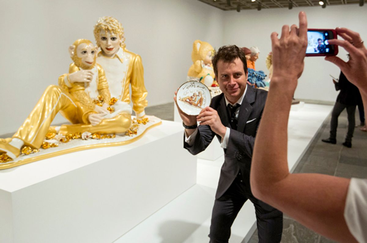 A man holds a signed plate with the likeness of the sculpture Michael Jackson and Bubbles in front of the actual sculpture at the Jeff Koons retrospective at the Whitney Museum of American Art in New York June 24, 2014.    (Reuters/Lucas Jackson)