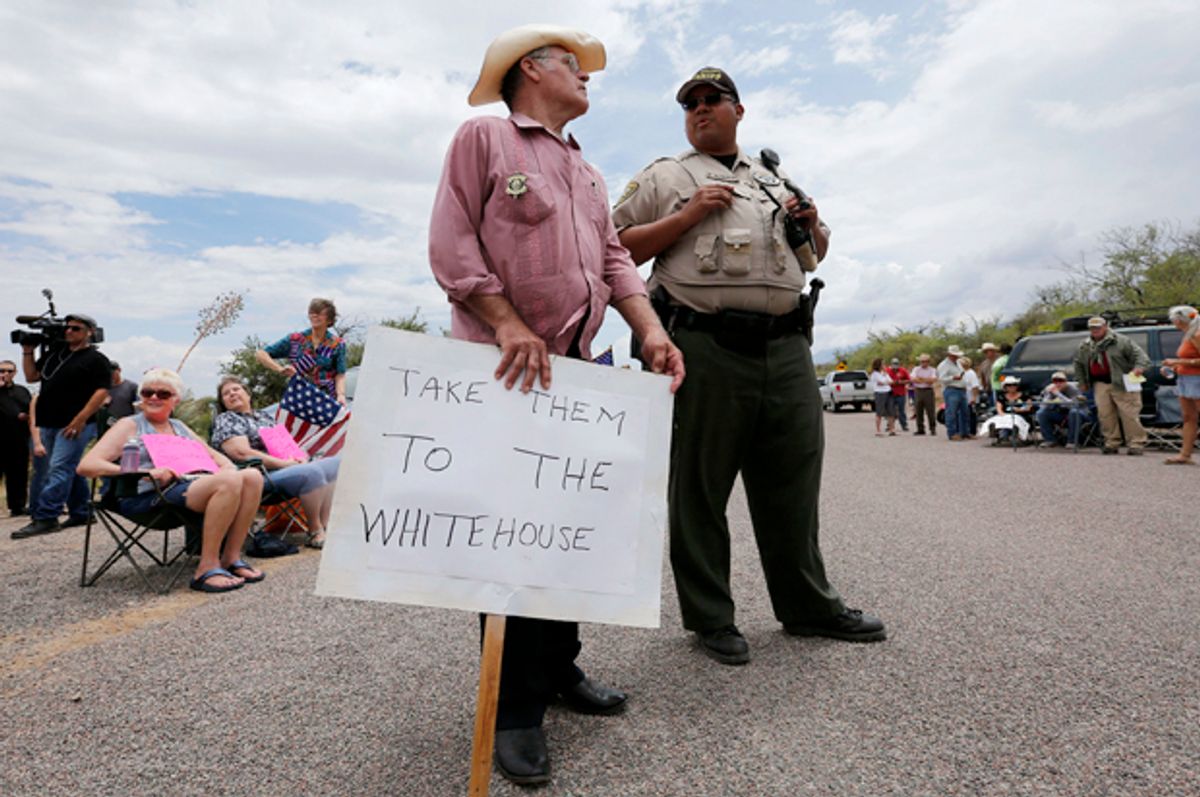Eldon Rhodes talks with a Pinal County Sheriff officer as people demonstrate against the arrival of undocumented immigrants in Oracle, Arizona July 15, 2014.      (Reuters/Nancy Wiechec)