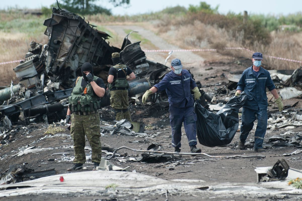 Ukrainian Emergency workers carry a stretcher with a victim's body in a bag as pro-Russian fighters stand in guard at the crash site of Malaysia Airlines Flight 17 near the village of Hrabove, eastern Ukraine, Sunday, July 20, 2014. Rebels in eastern Ukraine took control Sunday of the bodies recovered from downed Malaysia Airlines Flight 17, and the U.S. and European leaders demanded that Russian President Vladimir Putin make sure rebels give international investigators full access to the crash site.   ((AP Photo/Evgeniy Maloletka))