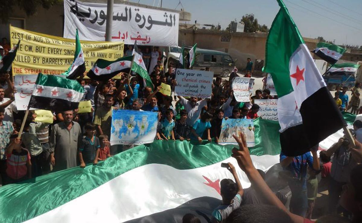 Anti-Syrian government protesters carry banners and a giant Syrian revolution flag during a demonstration in Idlib province, northern Syria.    (Associated Press)