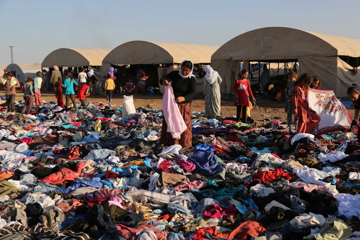 Displaced Iraqis from the Yazidi community look for clothes to wear among items provided by a charity organization at the Nowruz camp, in Derike, Syria, Tuesday, Aug. 12, 2014. In the camps here, Iraqi refugees have new heroes: Syrian Kurdish fighters who battled militants to carve an escape route to tens of thousands trapped on a mountaintop. While the U.S. and Iraqi militaries dropped food and water to the starving members of Iraqs Yazidi minority, the Kurds took it on themselves to rescue them, a sign of how Syrias Kurds, like Iraqs, are using the regions conflicts to establish their own rule. (AP Photo/ Khalid Mohammed) (AP)