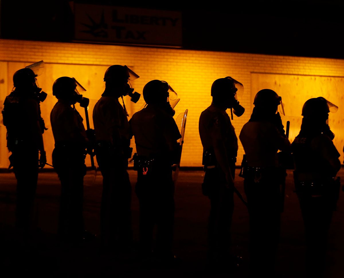 Police wait to advance after tear gas was used to disperse a crowd Sunday, Aug. 17, 2014, druing a protest for Michael Brown, who was killed by a police officer last Saturday in Ferguson, Mo. As night fell Sunday in Ferguson, another peaceful protest quickly deteriorated after marchers pushed toward one end of a street. Police attempted to push them back by firing tear gas and shouting over a bullhorn that the protest was no longer peaceful. (AP Photo/Charlie Riedel) (AP)