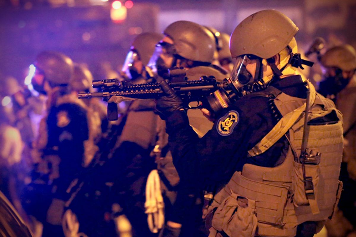 Police advance after tear gas was used to disperse a crowd Sunday, Aug. 17, 2014,  in Ferguson, Mo.                       (AP/Charlie Riedel)