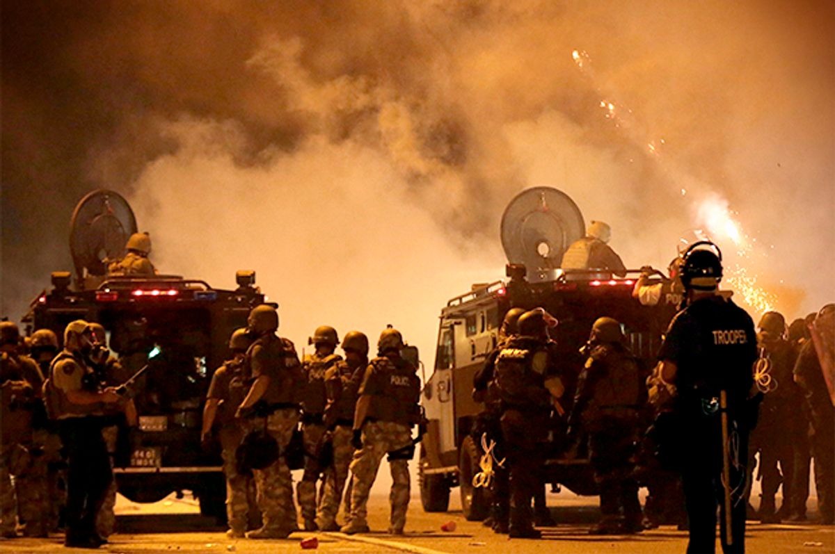 Police wait to advance after tear gas was used to disperse a crowd, Aug. 17, 2014, in Ferguson, Mo.                   (AP/Charlie Riedel)