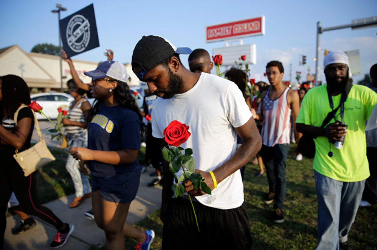 Protesters move down the street, many carrying roses, Aug. 18, 2014, in Ferguson, Mo.            (AP/Jeff Roberson)