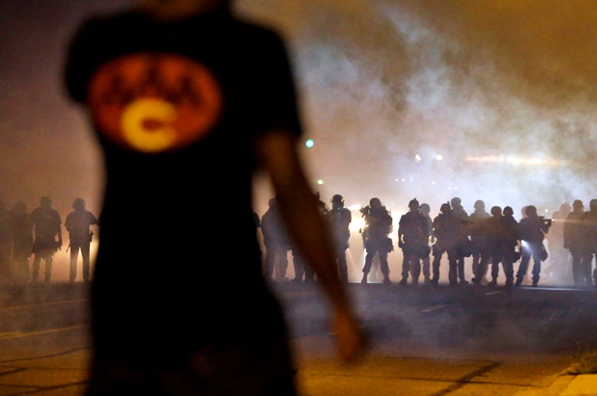 A man watches as police walk through a cloud of smoke during a clash with protesters, Aug. 13, 2014, in Ferguson, Mo.                         (AP/Jeff Roberson)