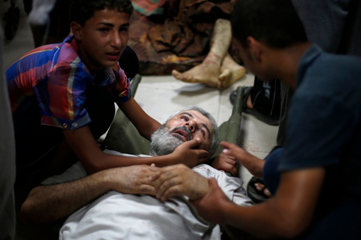 A Palestinian boy comforts his father, who medics said was wounded by Israeli shelling in Shejaia, at a hospital in Gaza City, July 30, 2014.            (Reuters/Suhaib Salem)