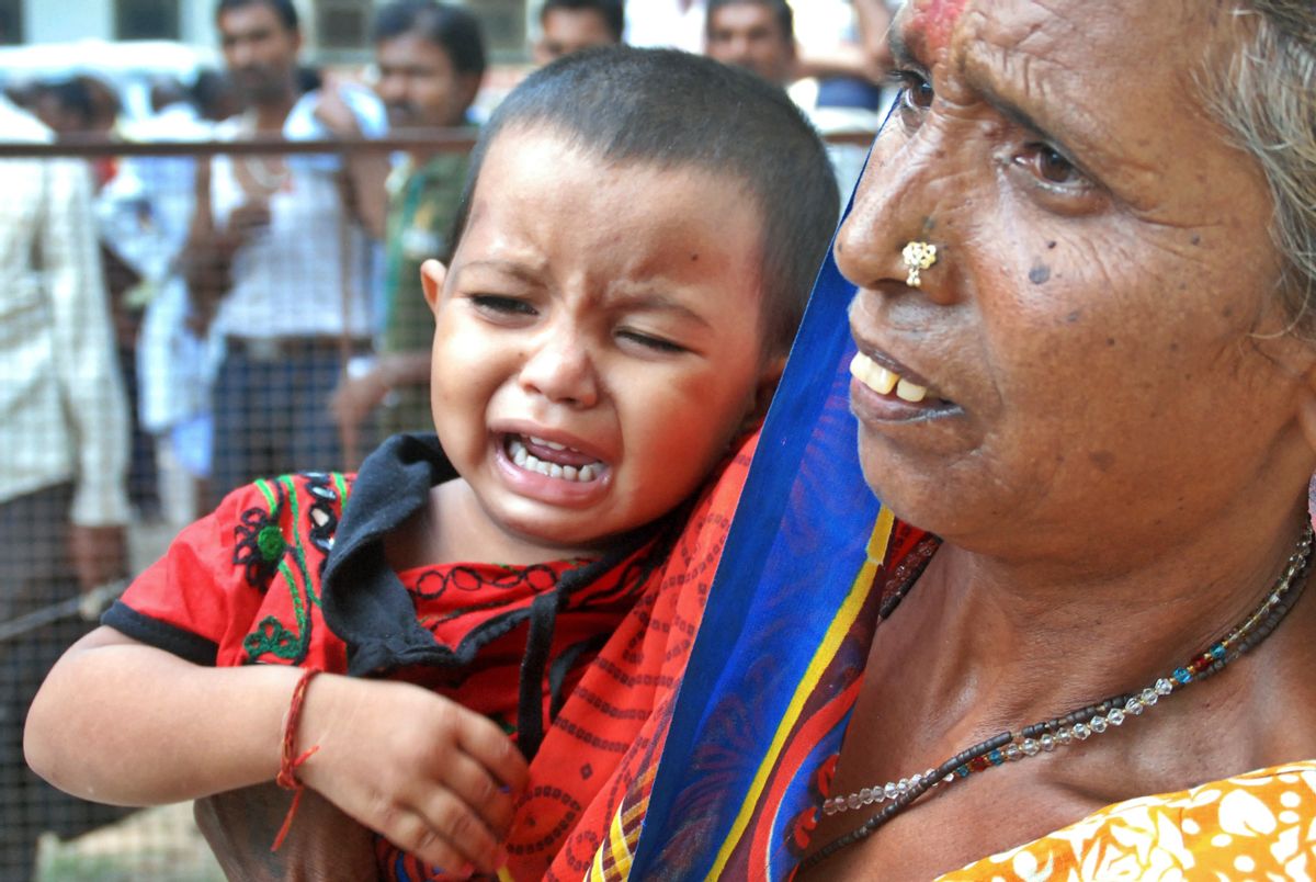 A woman holds a crying child as relatives of victims gather at the spot of a stampede at the Kamta Nath Hindu temple in Chitrakoot, India, Monday, Aug. 25, 2014. A pre-dawn stampede killed 10 people Monday as tens of thousands of Hindus were worshipping in an annual procession marking the holy day of Somvati Amavasya. (AP Photo/Amar Deep) (Amar Deep)