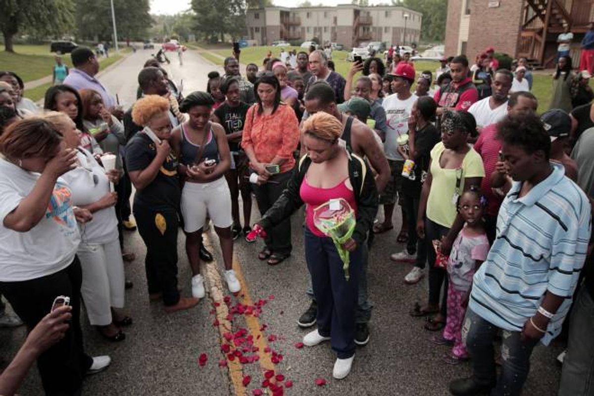 Lesley McSpadden, center, drops rose petals on the blood stains from her 18-year-old son Michael Brown who was shot and killed by police in the middle of the street in Ferguson, Mo., near St. Louis on Saturday, Aug. 9, 2014      (AP Photo/St. Louis Post-Dispatch, Huy Mach)