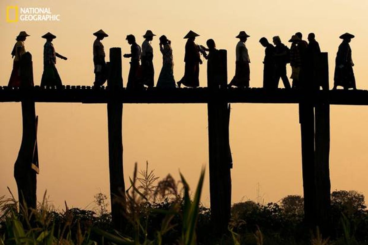 Ladies with Conical hats going to the right while locals, Monks, Kids, tourist going to the left as they were walking on the U Bien Bridge made out of teakwood at Mandalay, Myanmar   (April Badilles, National Geographic 2014 Photo Contest)