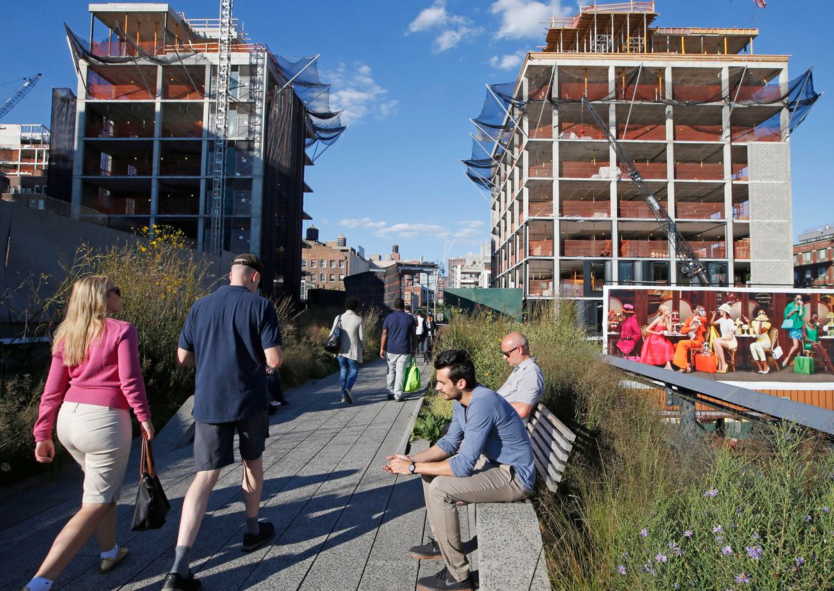 Pedestrians stroll along the High Line in New York, Wednesday, Sept. 17, 2014, as it winds between two buildings under construction. The last stretch of the elevated walkway opens to the public Sunday, Sept. 21. (AP Photo/Kathy Willens) (AP)