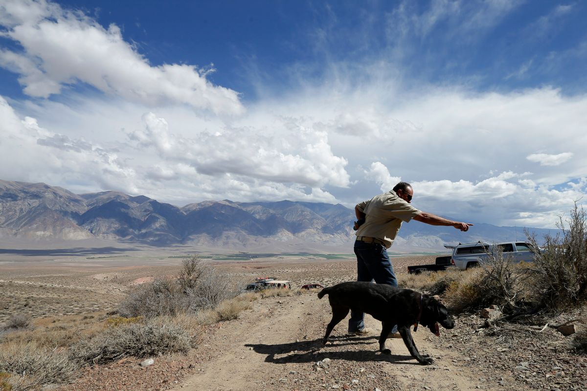 In this Sept. 20, 2014, photo, Paul Dotsie points as his dog Buster sets off to search an area near Bishop, Calif. For years, Buster and Dostie have worked together to unlock mysteries, to find the bodies of fighting men who fell long ago on foreign battlefields, or of victims of unsolved crimes or disappearances. In all, Dostie said that Buster has helped find the remains of about 200 people. (AP Photo/Gregory Bull) (AP)