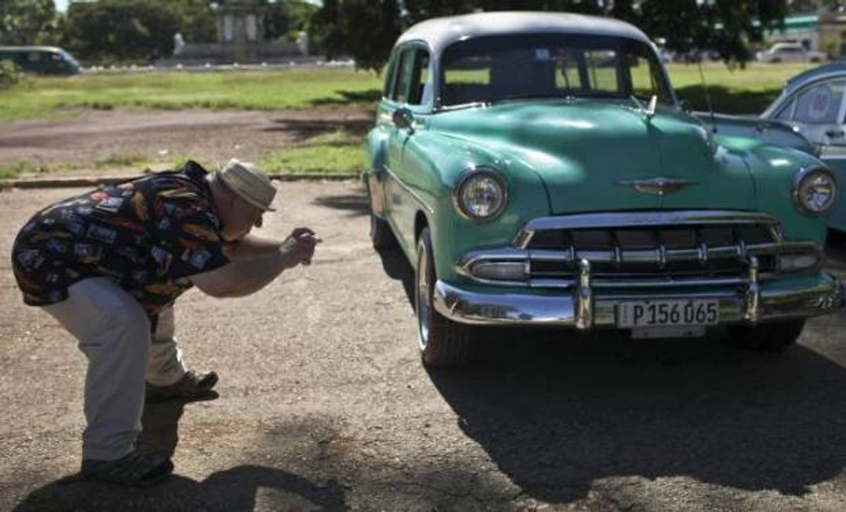 A tourist takes a picture of  a classic American car in Havana (AP)