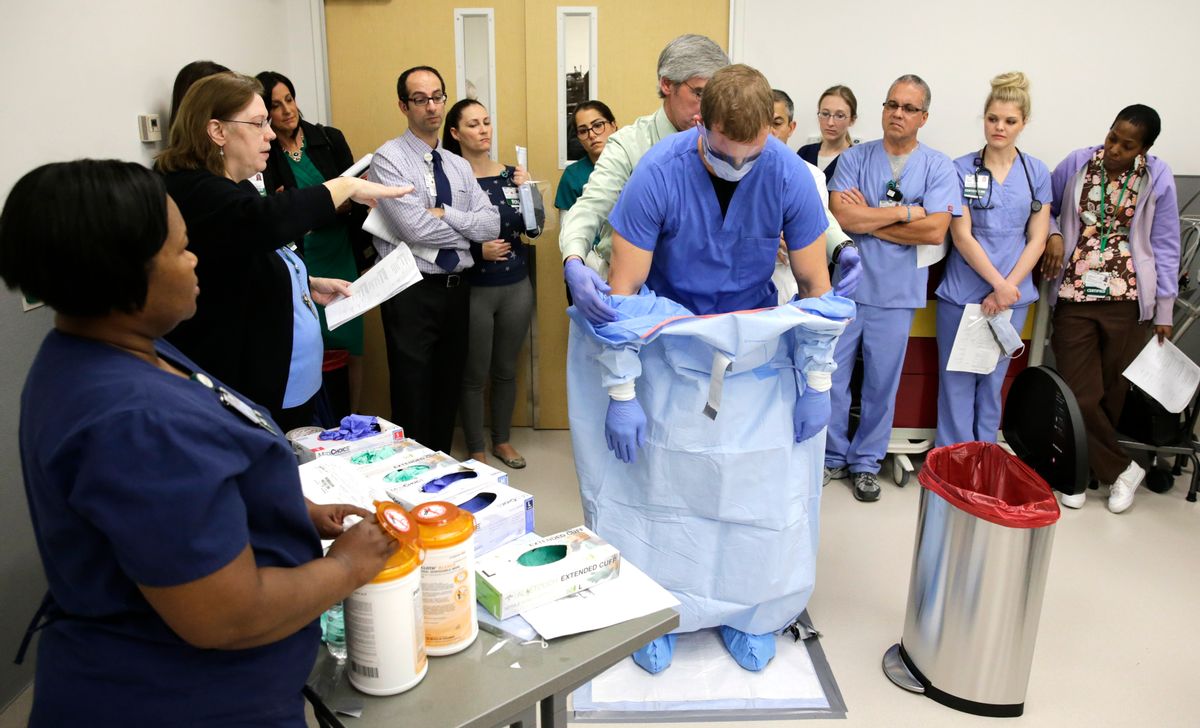 Registered nurse Keene Roadman, dressed in personal protective equipment, and registered nurse Fred Serafin, demonstrates the proper disposal of the personal protective equipment, after the simulated treatment of a Ebola patient, to doctors and nurses who are part of the core care team that would treat Ebola patients, during a training class at the Rush University Medical Center, Thursday, Oct. 16, 2014, in Chicago. () (AP Photo/Charles Rex Arbogast)