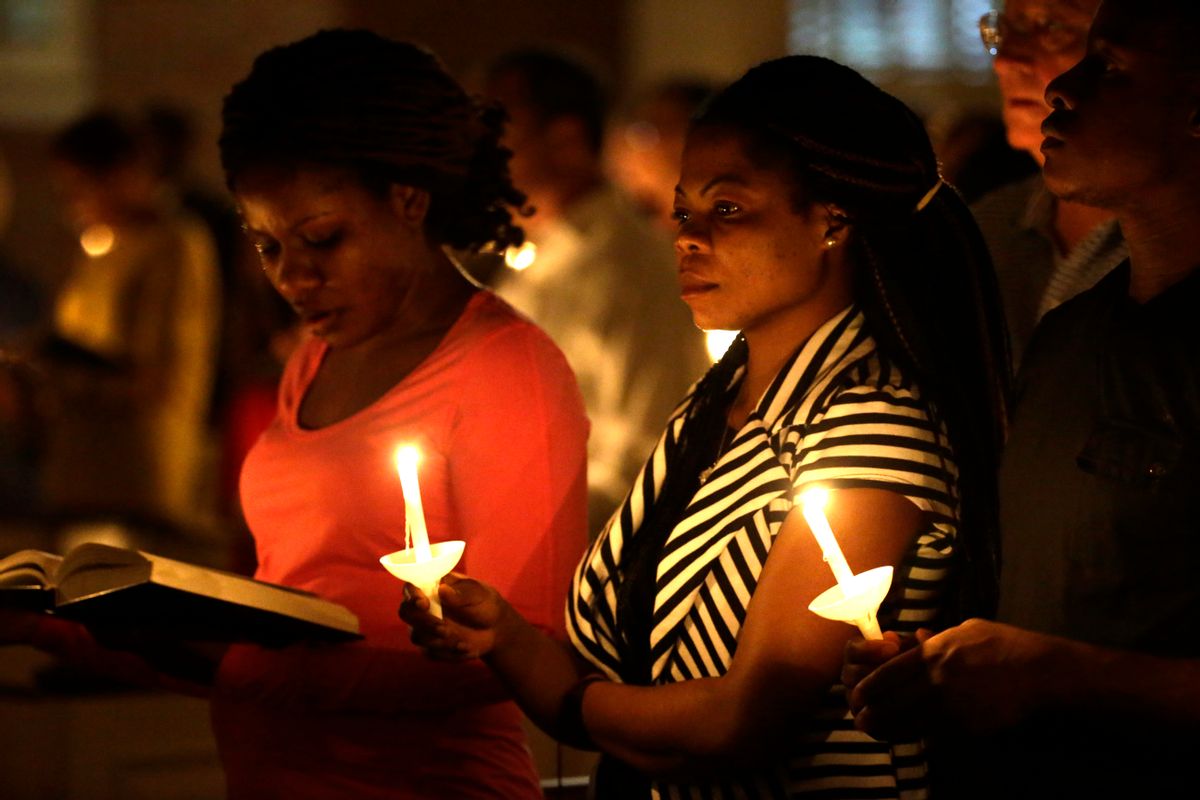Princess Duo, left, and Mamie Mangoe, right, both natively of Liberia who now live in Dallas, stand holding lit candles as they pray during a service at Wilshire Baptist Church that was dedicated to Thomas Eric Duncan, Wednesday, Oct. 8, 2014, in Dallas. Nearly 150 persons attended the service for Duncan who died Wednesday of complication from Ebola.  (AP Photo/Tony Gutierrez) (AP)