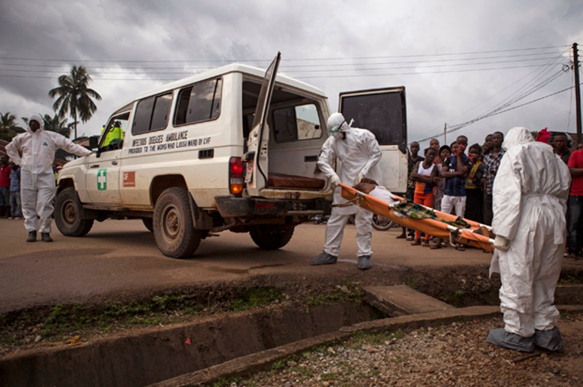 Healthcare workers load a man suspected of suffering from the Ebola virus onto an ambulance in Kenema, Sierra Leone, Sept. 24, 2014.                 (AP/Tanya Bindra)